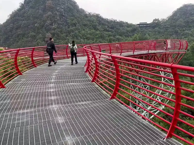 public infrastructure bridge walkway with galvanized steel grating floor and red guardrails